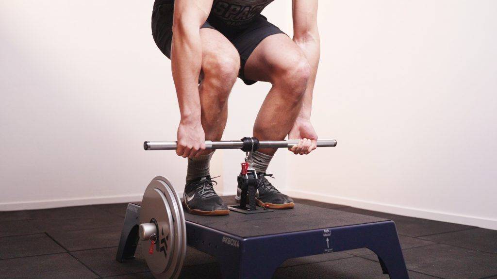 Man deadlifting with a mixed grip using a knurled kBar on a kBox4 Pro loaded with high inertia